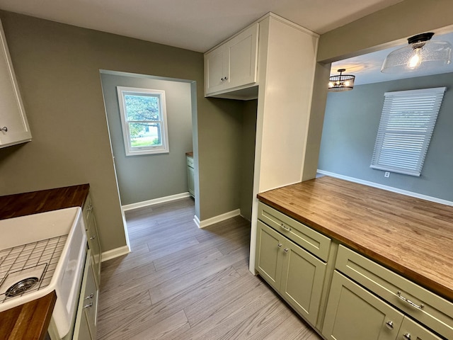 kitchen featuring baseboards, light wood-style flooring, and butcher block counters
