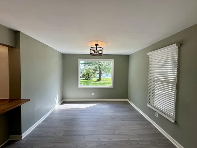 unfurnished dining area featuring baseboards, dark wood-style floors, and a notable chandelier