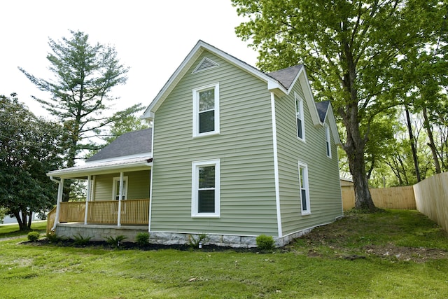 back of property featuring a lawn, a shingled roof, fence, and covered porch