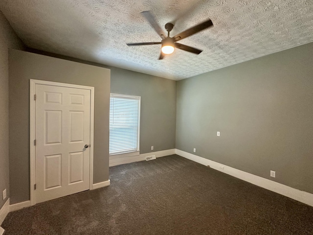 spare room featuring ceiling fan, a textured ceiling, dark carpet, baseboards, and visible vents