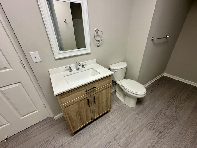 bathroom with baseboards, wood finished floors, and toilet