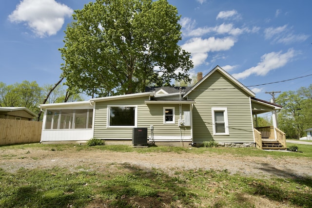 rear view of house featuring fence, cooling unit, a chimney, and a sunroom