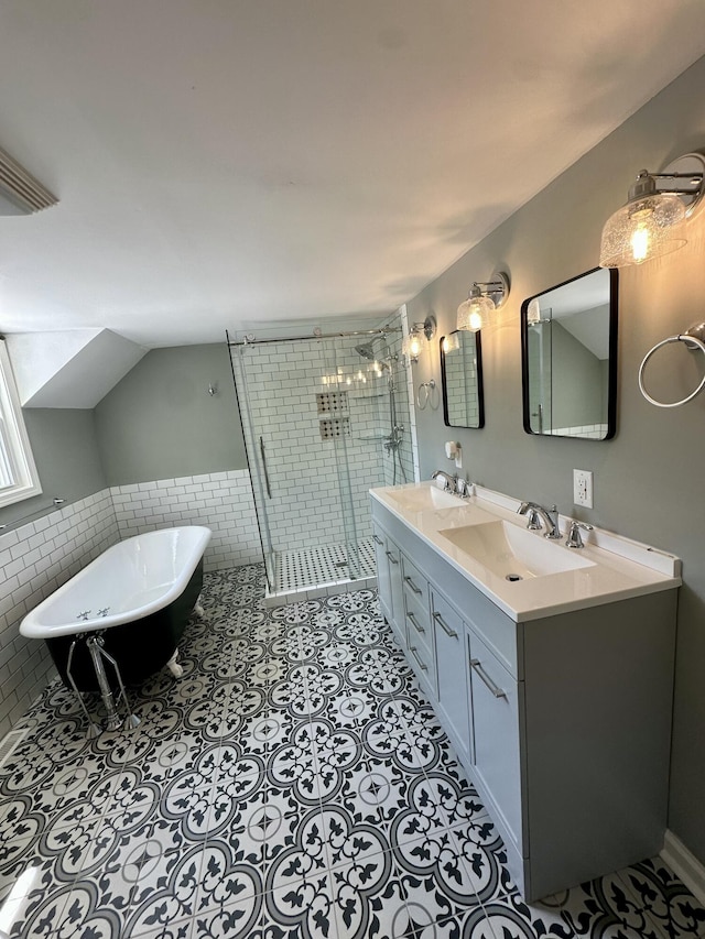 full bathroom featuring double vanity, a freestanding tub, tile walls, a shower stall, and a sink