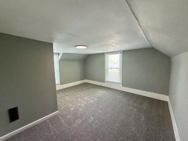additional living space with baseboards, lofted ceiling, carpet flooring, and visible vents