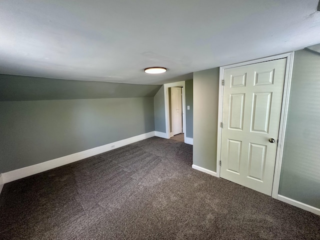 bonus room with baseboards and dark colored carpet