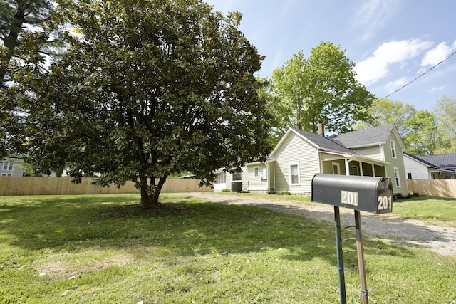view of side of property featuring fence, a yard, and driveway
