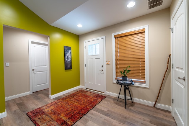 foyer entrance featuring visible vents, baseboards, and wood finished floors