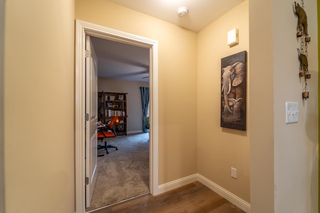 corridor featuring baseboards and dark wood finished floors