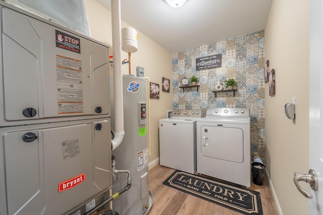 clothes washing area with laundry area, heating unit, separate washer and dryer, light wood-style flooring, and electric water heater