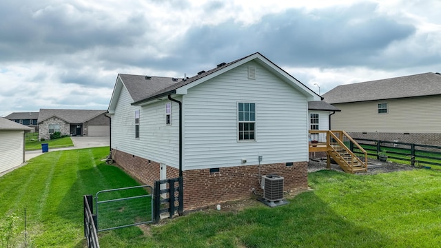 back of house featuring central AC, stairway, crawl space, a fenced backyard, and a yard