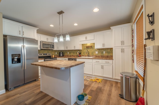 kitchen with a sink, white cabinetry, appliances with stainless steel finishes, and wood finished floors