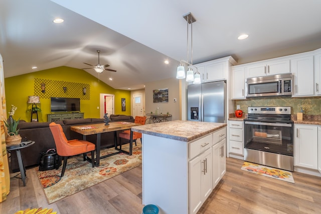 kitchen featuring a kitchen island, open floor plan, light wood-type flooring, a ceiling fan, and appliances with stainless steel finishes