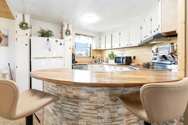 2805 W W Ridge Rd, Eubank, KY 42567 - kitchen featuring a peninsula, butcher block countertops, under cabinet range hood, white cabinets, and appliances with stainless steel finishes