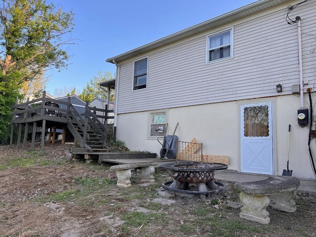 rear view of property with stairway, a wooden deck, and an outdoor fire pit