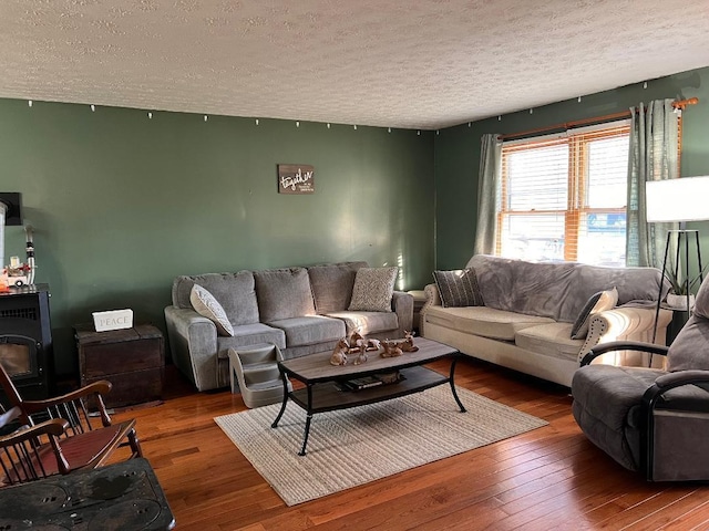living area featuring a wood stove, hardwood / wood-style flooring, and a textured ceiling