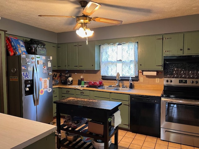 kitchen featuring light countertops, green cabinetry, under cabinet range hood, a sink, and stainless steel appliances