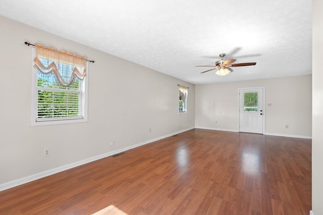 spare room featuring visible vents, wood finished floors, baseboards, ceiling fan, and a textured ceiling