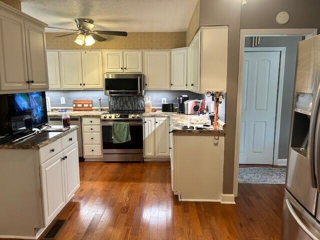 kitchen featuring visible vents, dark wood-style floors, white cabinetry, a ceiling fan, and appliances with stainless steel finishes