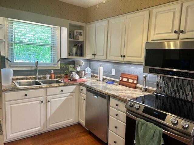 kitchen featuring open shelves, light wood-type flooring, a sink, appliances with stainless steel finishes, and backsplash