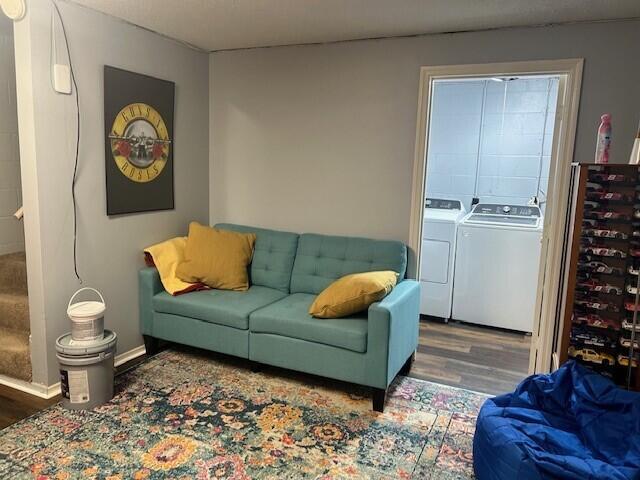 living area with independent washer and dryer and wood finished floors