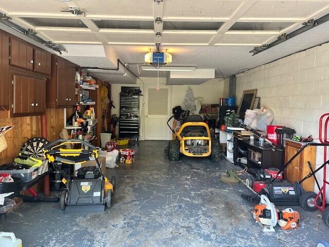 garage featuring concrete block wall and a garage door opener