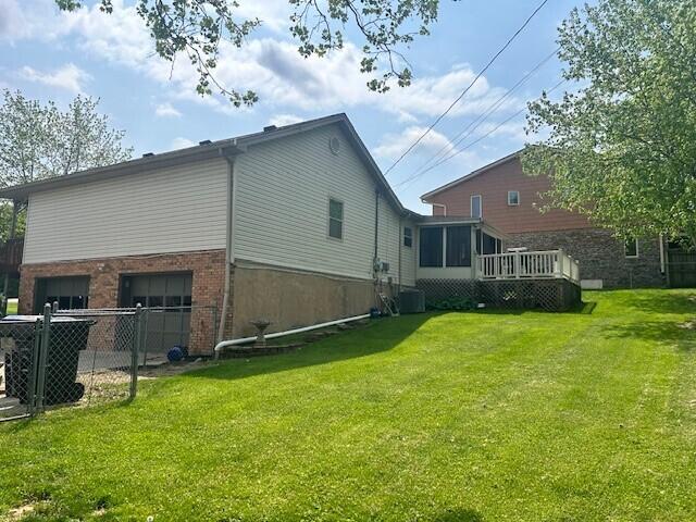 view of property exterior with brick siding, a garage, a lawn, and fence