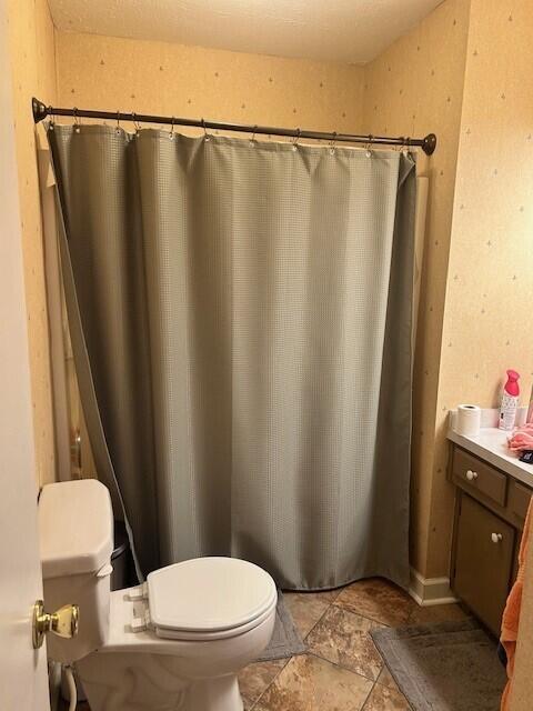 full bath with stone finish floor and toilet