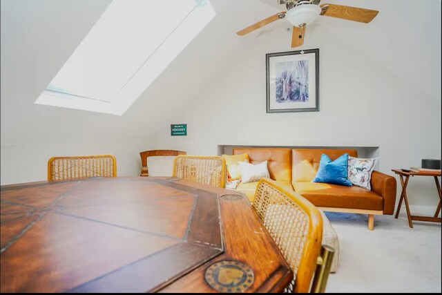 dining space featuring vaulted ceiling with skylight, ceiling fan, and carpet flooring