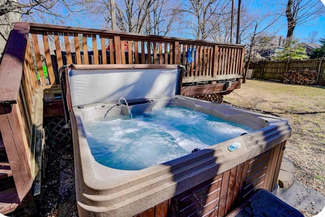 deck with a hot tub and fence