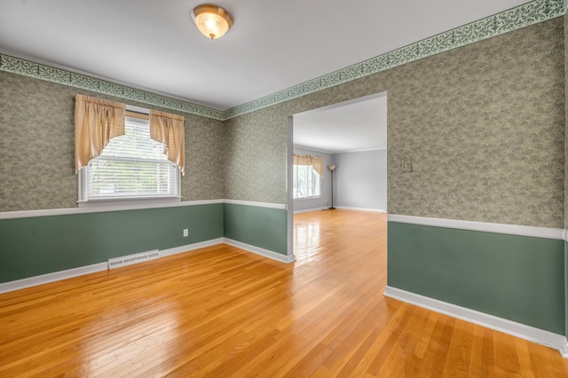 spare room with baseboards, wallpapered walls, and wood finished floors