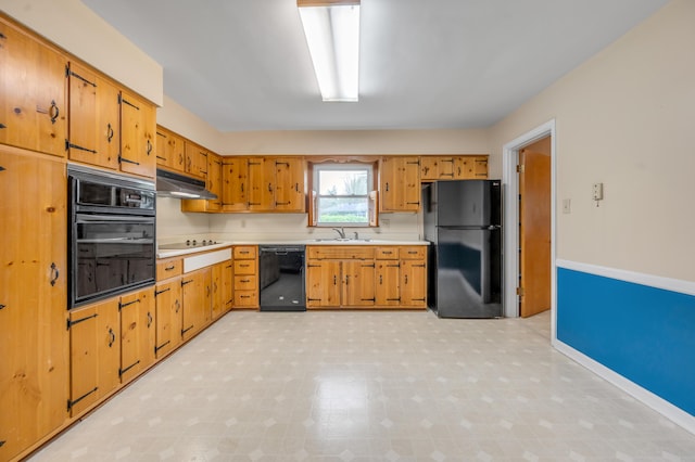 kitchen with a sink, light countertops, light floors, under cabinet range hood, and black appliances