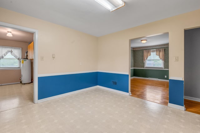 spare room with baseboards, visible vents, tile patterned floors, and gas water heater