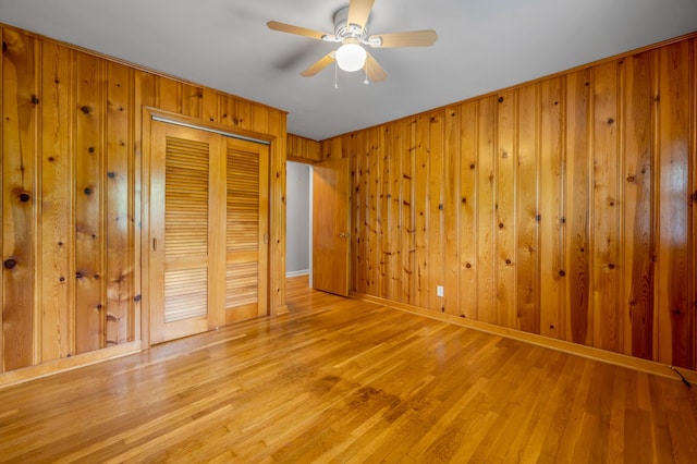unfurnished bedroom featuring wooden walls, a closet, and light wood finished floors