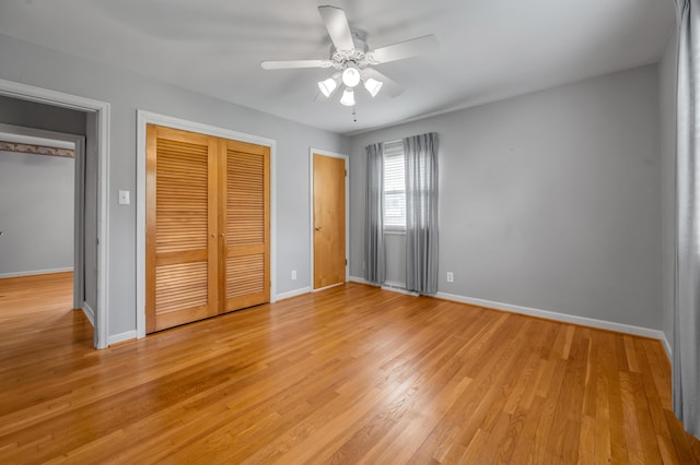 unfurnished bedroom featuring baseboards, ceiling fan, a closet, and light wood-style flooring
