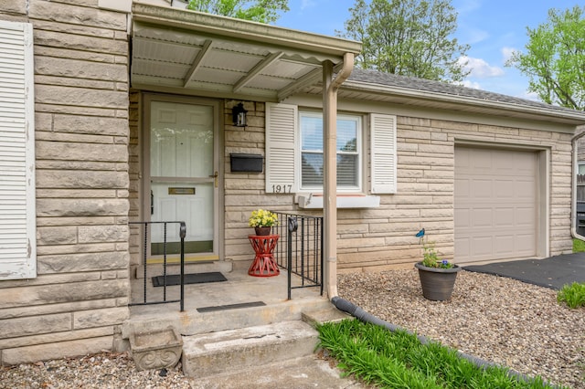 doorway to property featuring an attached garage and aphalt driveway