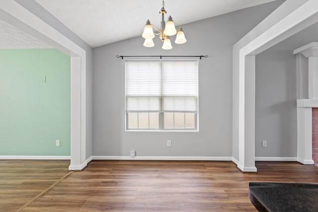 unfurnished dining area with baseboards, vaulted ceiling, wood finished floors, and a chandelier