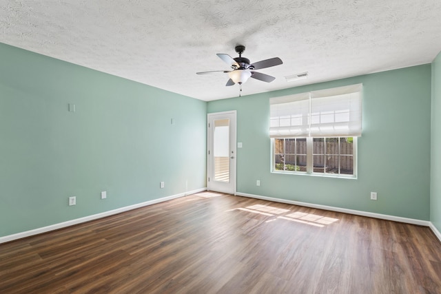 empty room featuring a ceiling fan, a textured ceiling, visible vents, wood finished floors, and baseboards