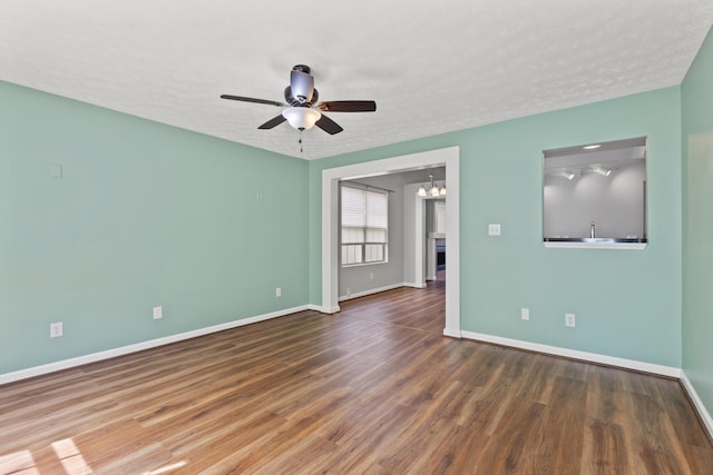 unfurnished room with baseboards, a textured ceiling, ceiling fan with notable chandelier, and wood finished floors
