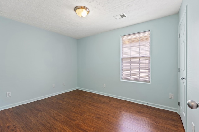 spare room with baseboards, wood finished floors, and visible vents
