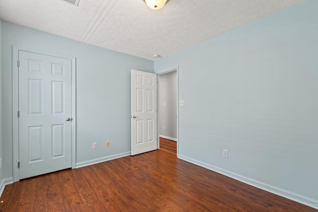 unfurnished bedroom featuring baseboards, a textured ceiling, and wood finished floors