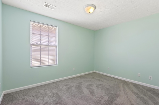 carpeted empty room with baseboards, a textured ceiling, and visible vents