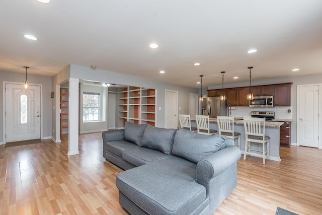 living room featuring baseboards, recessed lighting, and light wood-type flooring