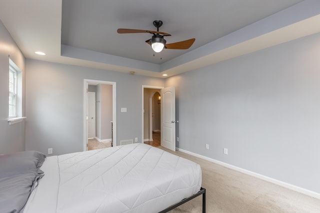 bedroom featuring baseboards, a tray ceiling, recessed lighting, and arched walkways