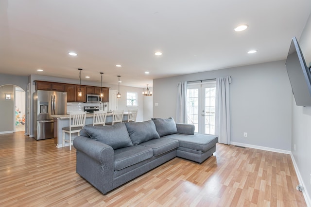 living area featuring recessed lighting, arched walkways, and light wood-style flooring