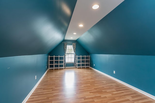 bonus room with baseboards, wood finished floors, and vaulted ceiling