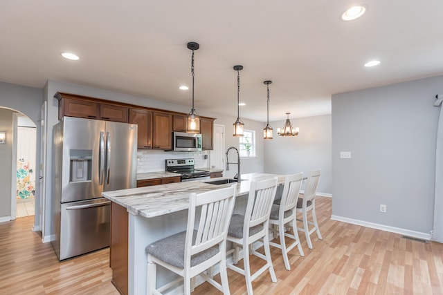 kitchen featuring a sink, arched walkways, light wood-style flooring, stainless steel appliances, and visible vents