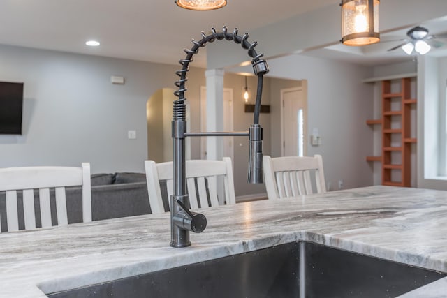 kitchen featuring light stone counters, arched walkways, ceiling fan, and recessed lighting