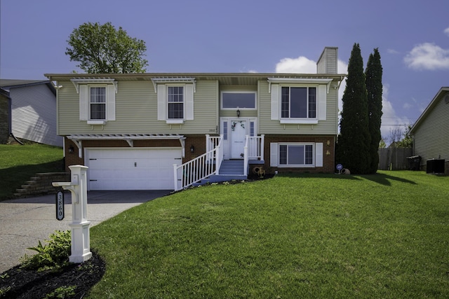 split foyer home featuring a front lawn, a chimney, brick siding, an attached garage, and driveway
