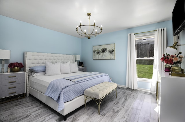 bedroom featuring baseboards, wood finished floors, and a chandelier