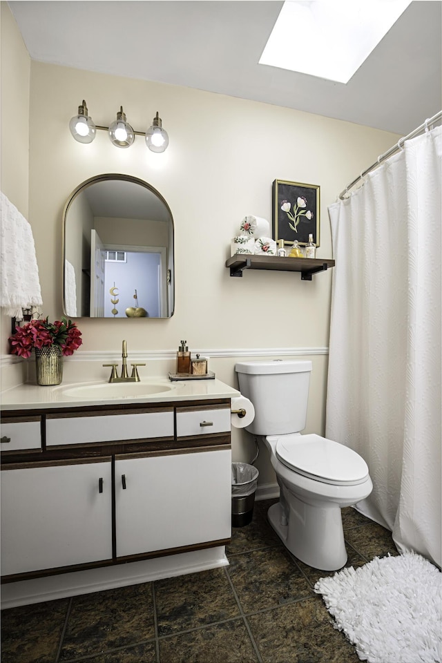bathroom featuring a skylight, vanity, tile patterned floors, and toilet